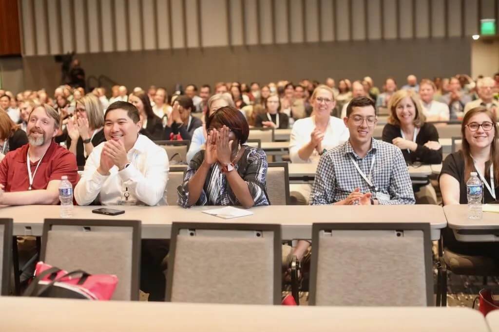 Attendees smile and clap during a plenary session.
