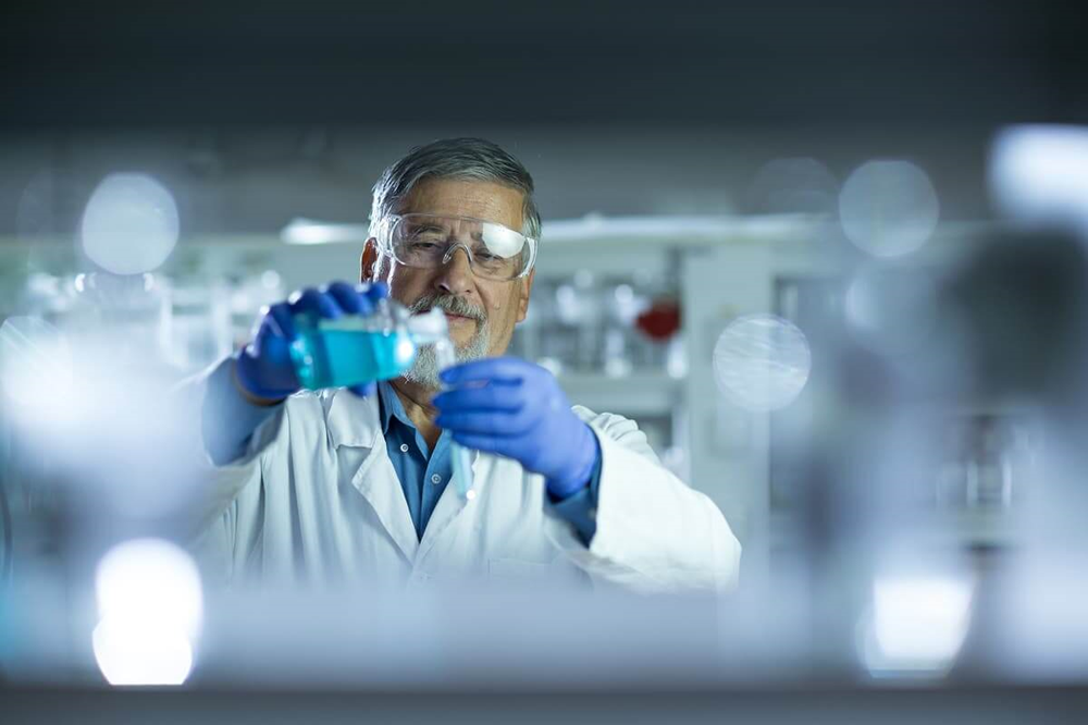 Scientist pouring liquid from bottle to beaker