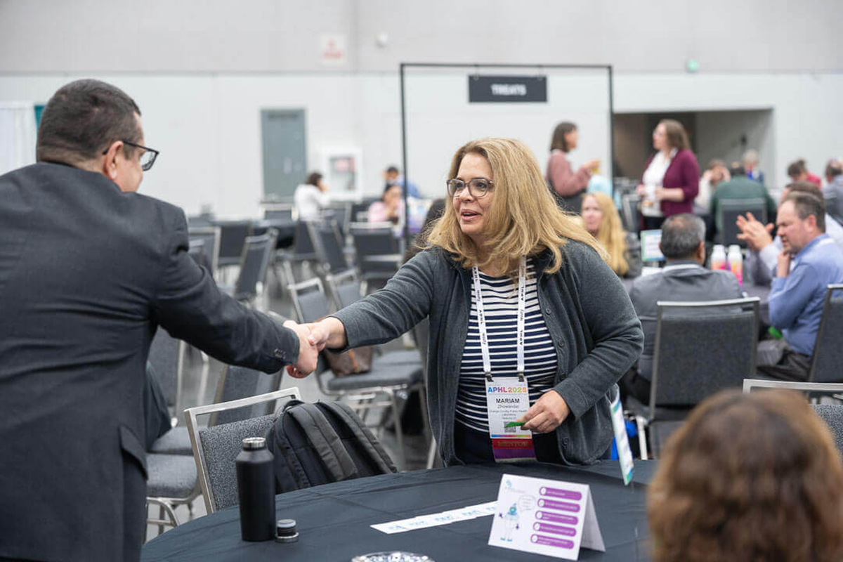 At a networking event, two people shake hands.