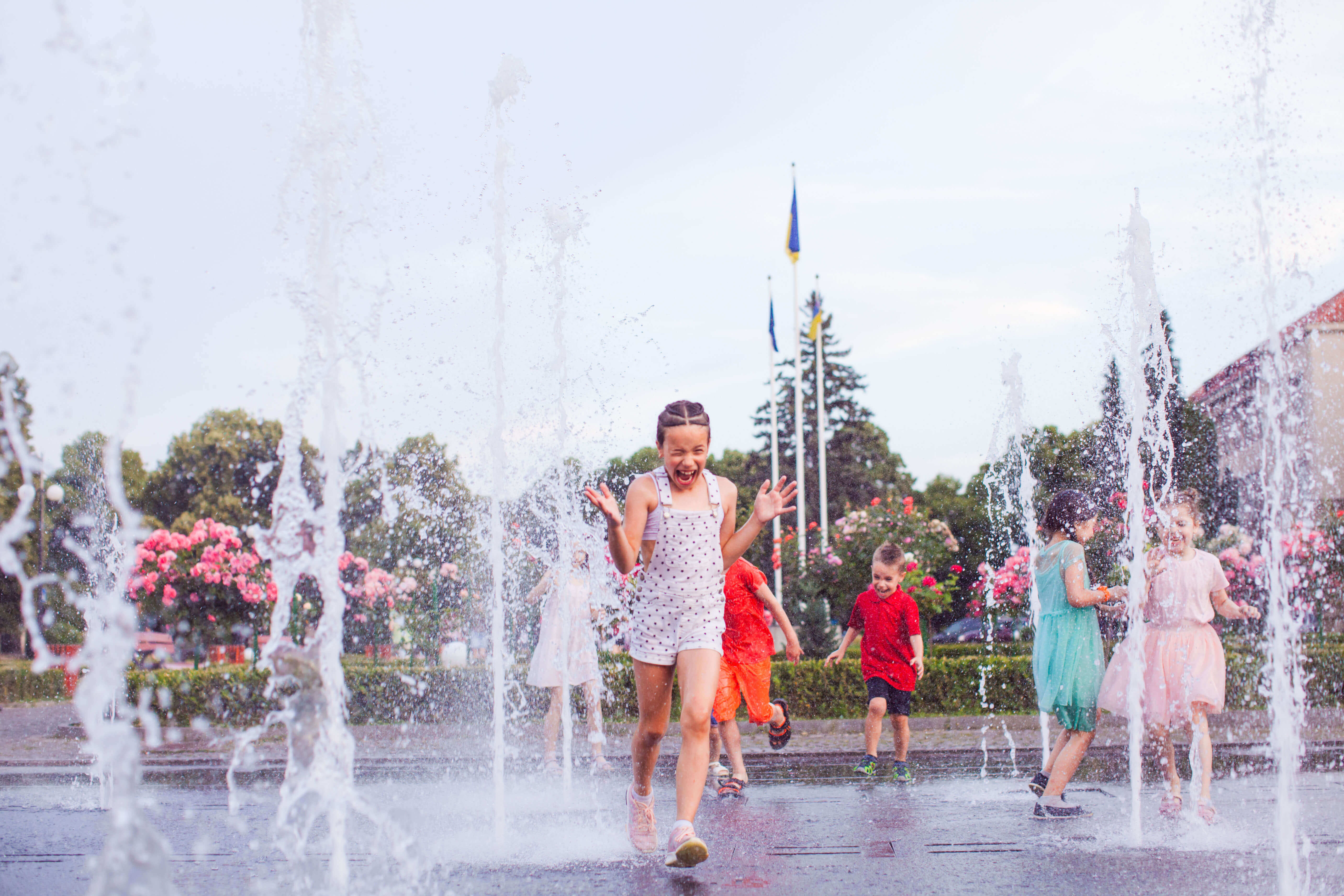 young children run through water at a splash pad in summer