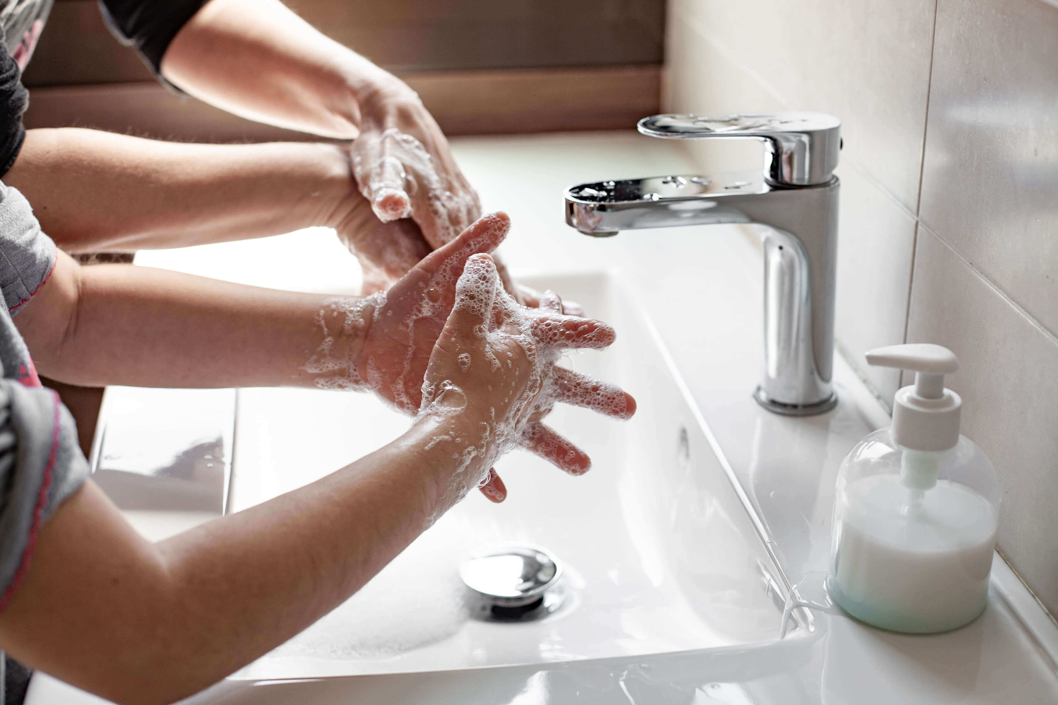 Child washing hands with a parent