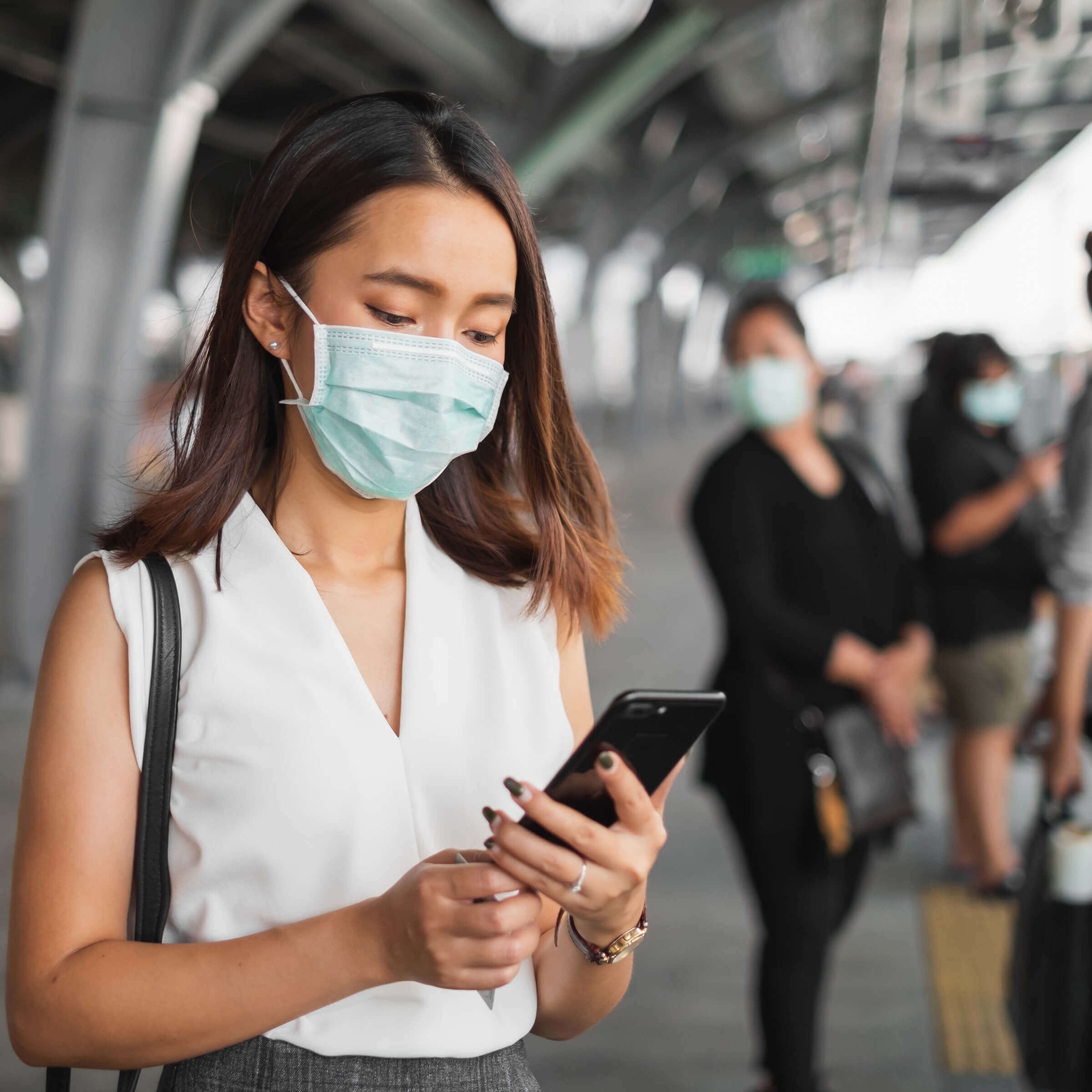 woman with a mask on holding a phone