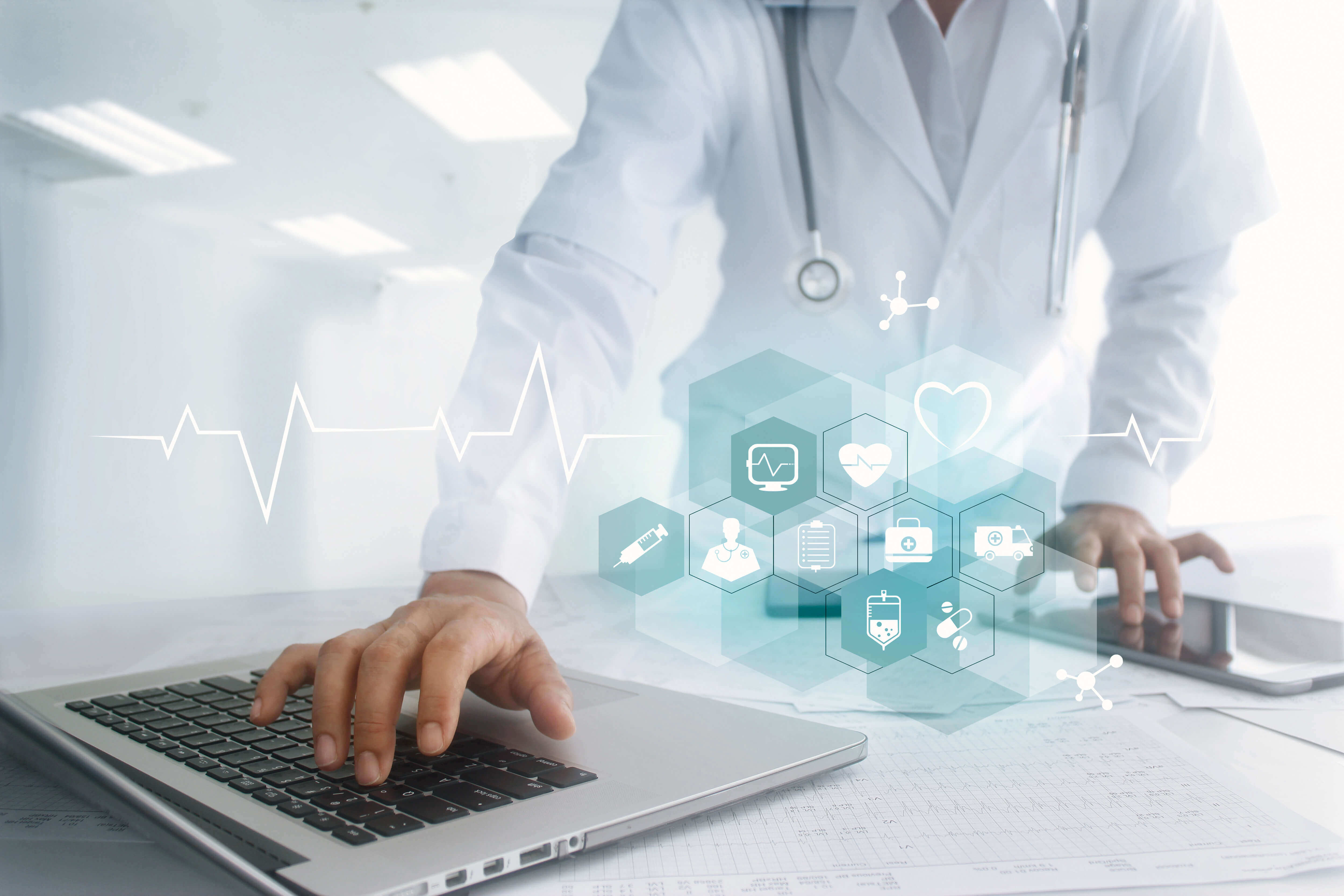 male scientist types on a laptop with healthcare icons overlaid