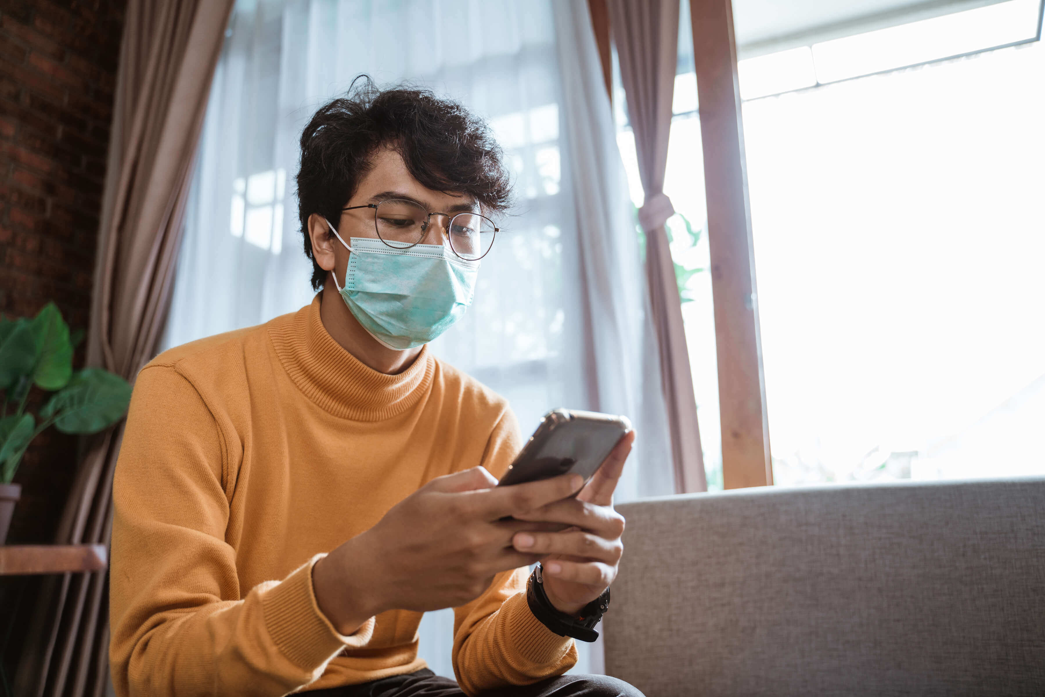 man in face mask looks at phone