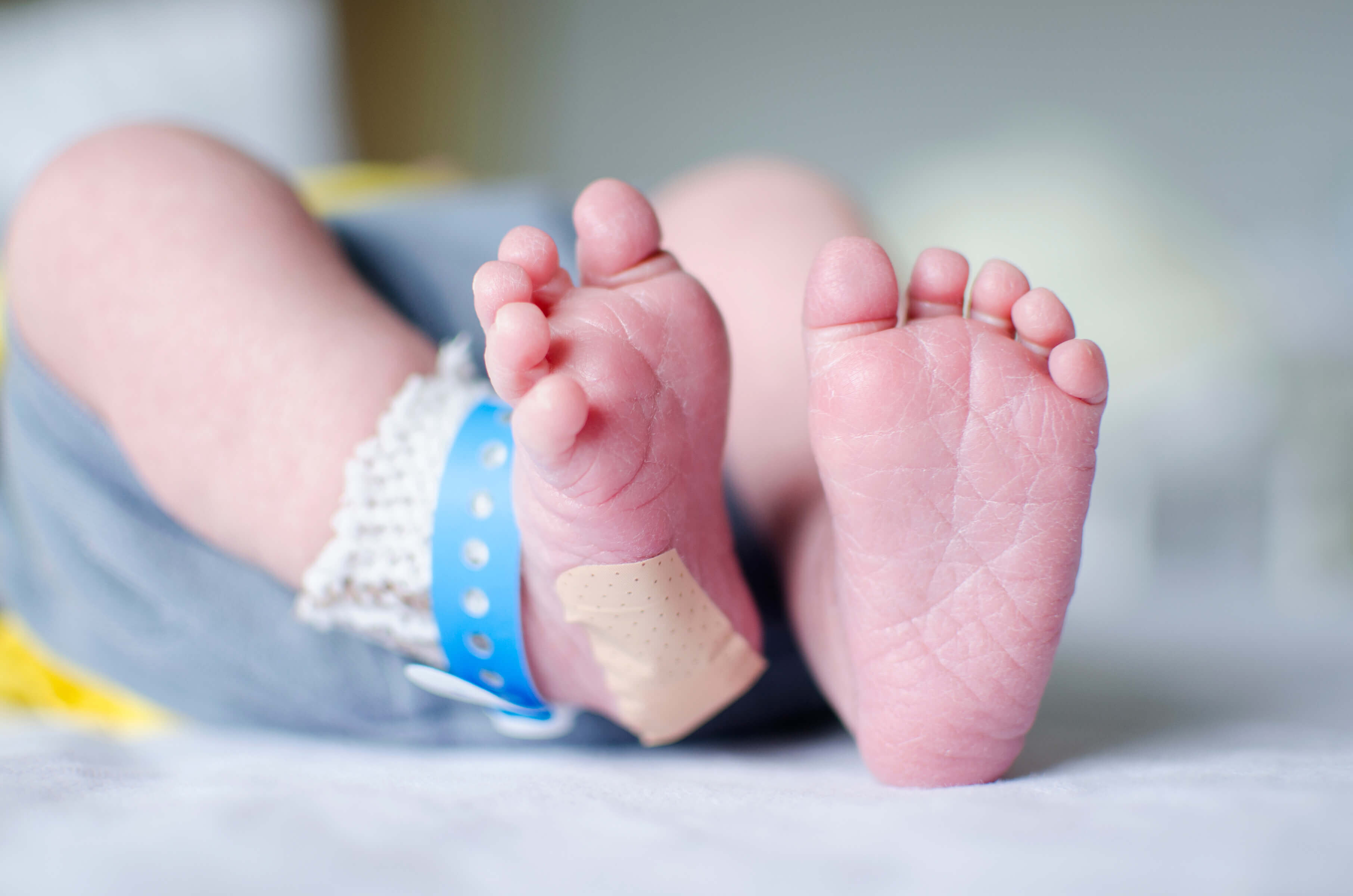 baby feet with bandage on heel and hospital band on ankle