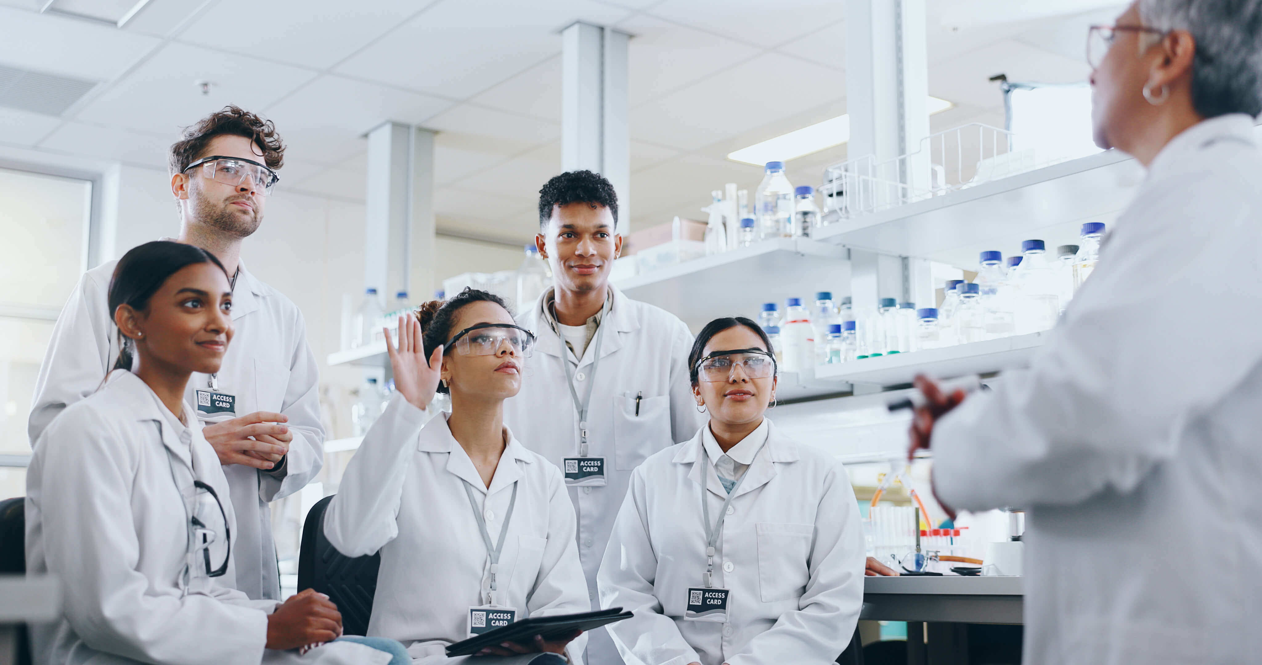 laboratory students listening to instructor and raising hand to ask a question