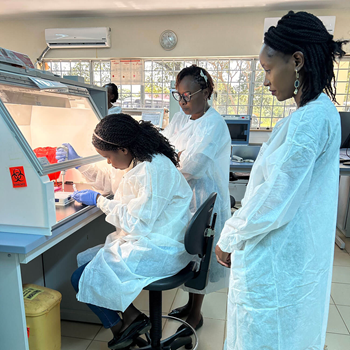 APHL’s senior laboratory specialist, Beatrice Oduor, looking over as participants do practical work in the laboratory.