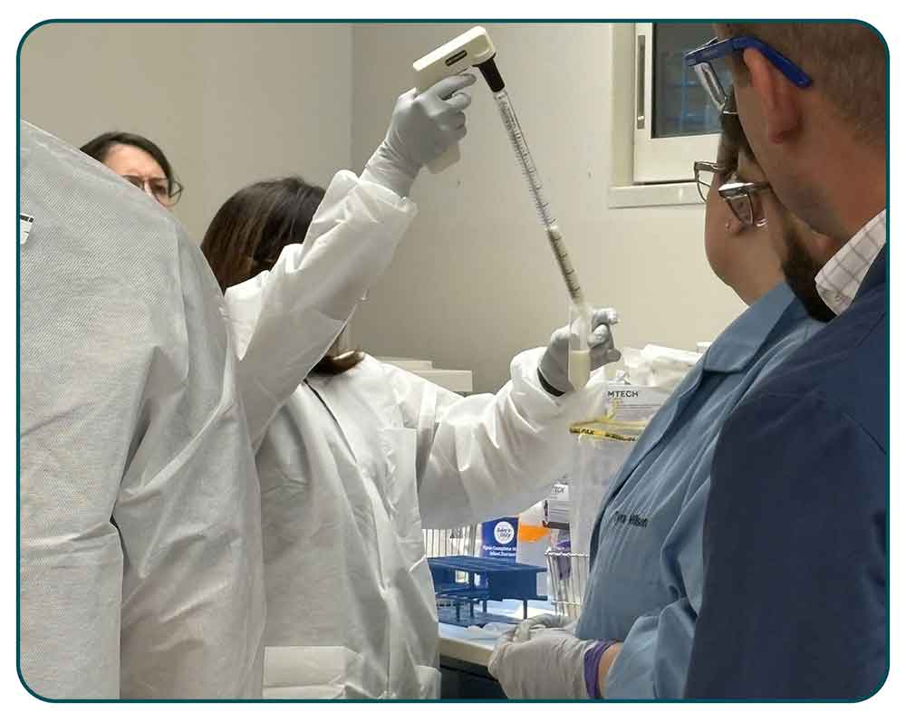 An instructor demonstrates how to remove supernatants from a powdered infant formula enrichment.